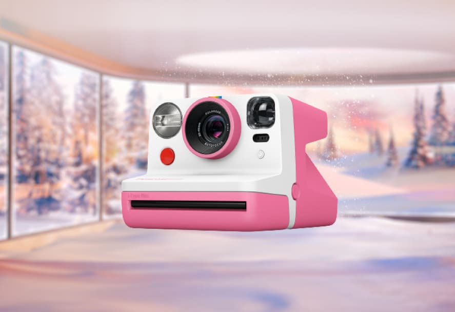A pink and white instant Polaroid camera on a festive backdrop