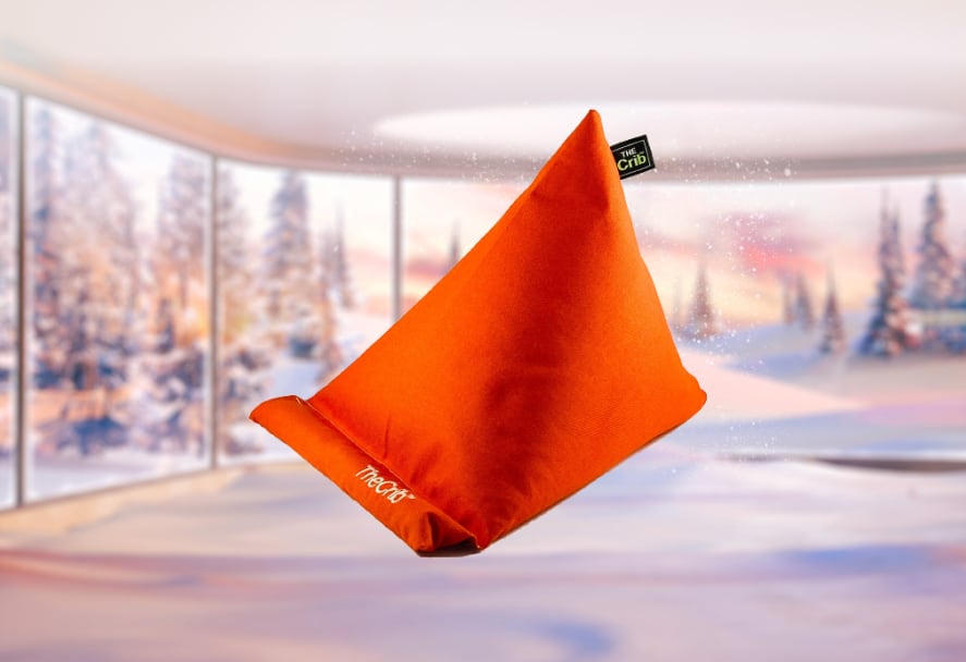 An orange mini beanbag phone holder displayed on a festive backdrop
