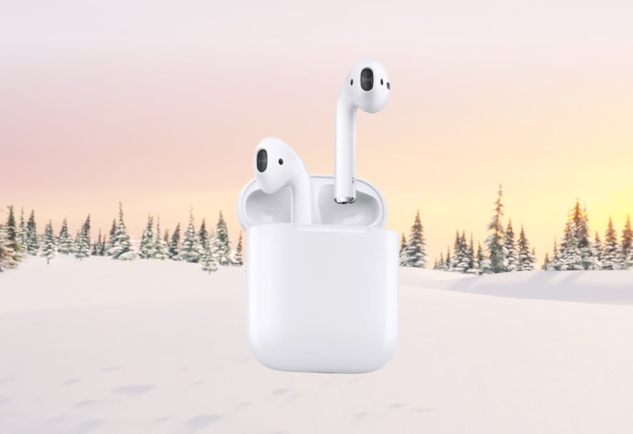A white pair of AirPods 2 with a charging case on a snowy mountain backdrop