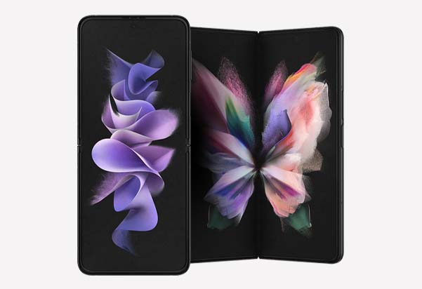 The Samsung Galaxy Z Flip3 and Z Fold3 in Phantom Black, displayed side by side — the Flip3 folded vertically and the Fold3 fully unfolded, both showing vibrant floral wallpapers on their displays.