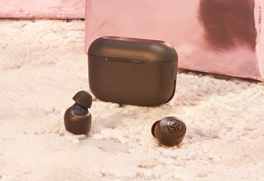 A black pair of Jlab Go air pop earphones sitting on a white fur carpet