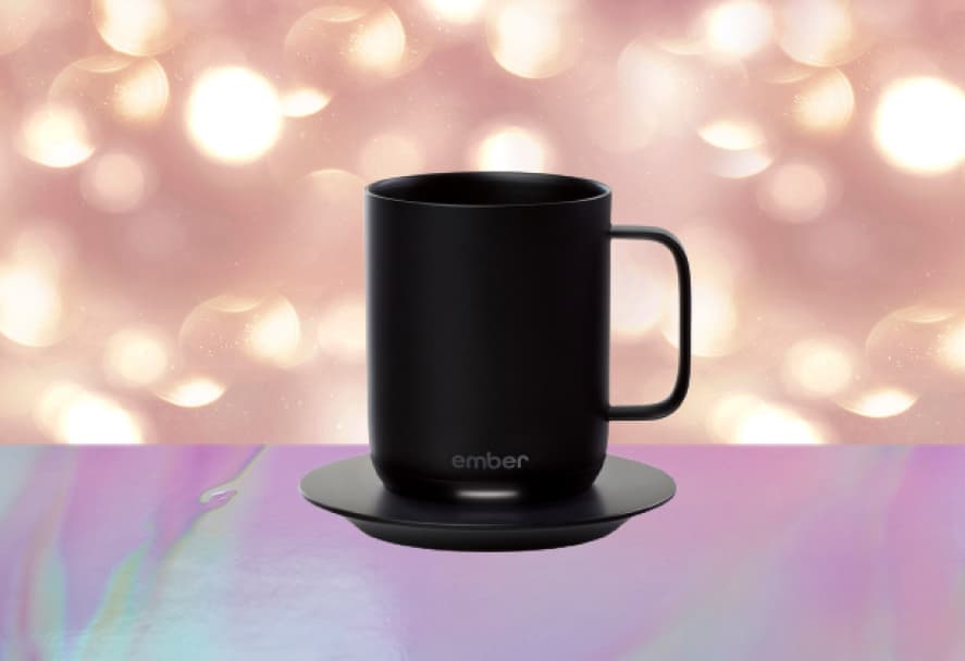 A black smart coffee cup by Ember that sits on a charging saucer