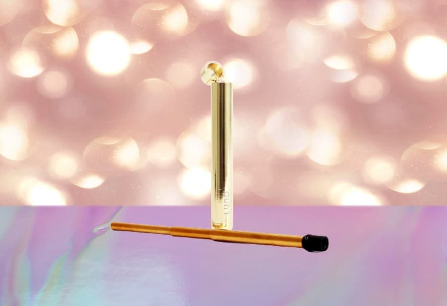 A gold reusable and collapsible eco straw on a sparkle backdrop