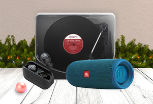 An ION portable turntable, JBL Flip Bluetooth speaker in teal, and black wireless earbuds displayed together in a festive Christmas setting.