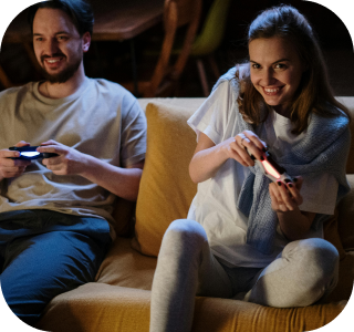 A young couple sits on a mustard yellow couch, playing video games. A young couple sits on a mustard yellow couch, playing video games.
