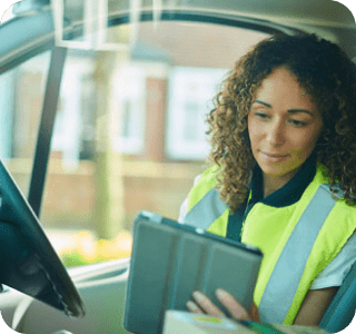 Person sitting in a van, wearing a hi-vis vest looking at a tablet Person sitting in a van, wearing a hi-vis vest looking at a tablet