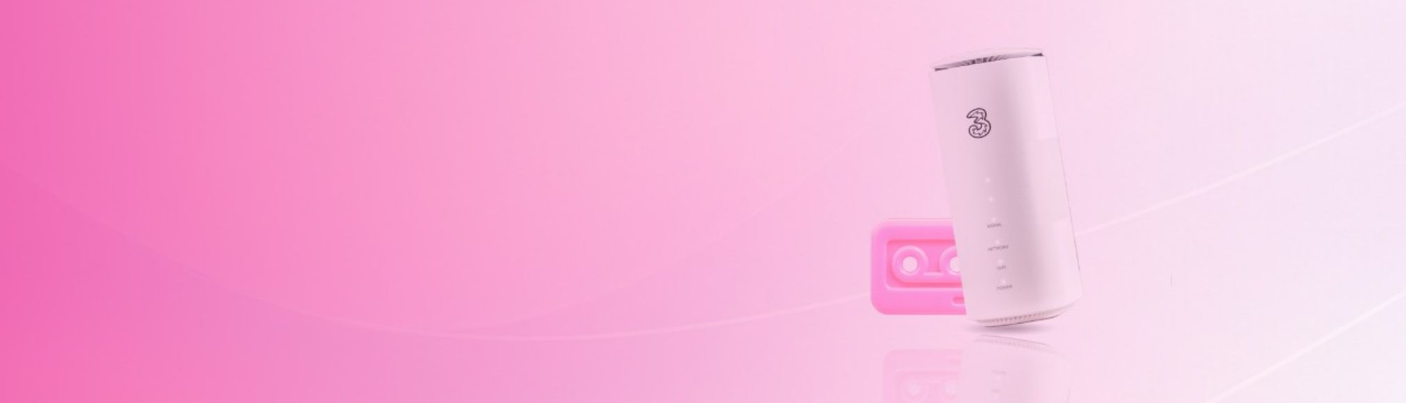 A white Three home broadband router standing vertically next to a pink cassette tape, set against a bright pink gradient background.
