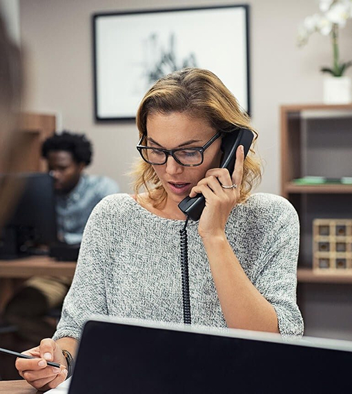 A person is seated at a desk, engaged in a phone conversation
