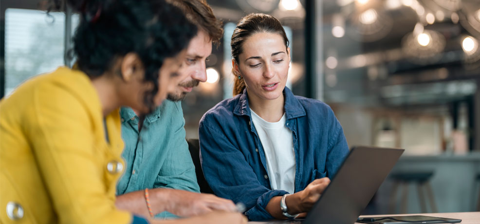 Three people sitting together looking at a laptop