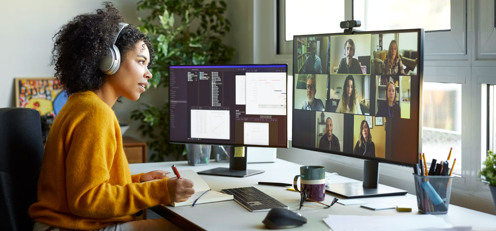 Person sitting at a desk wearing headphones, participating in an online meeting
