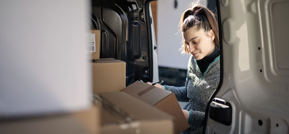 Person loading boxes in a van, holding a pen