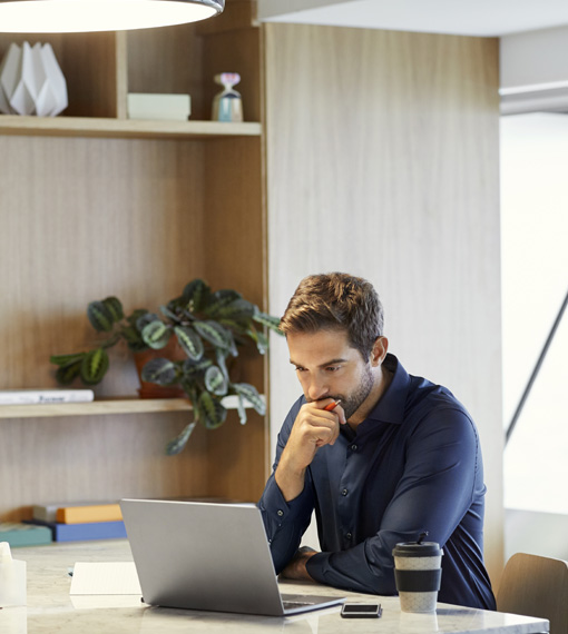 Person sitting at a desk looking intently at a laptop