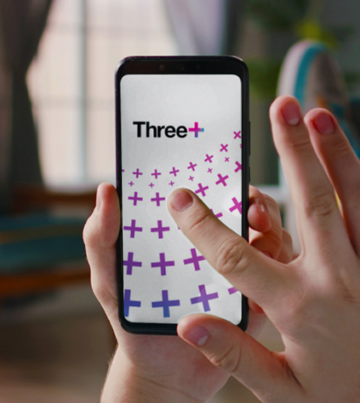Person holding a phone loading the Three+ App