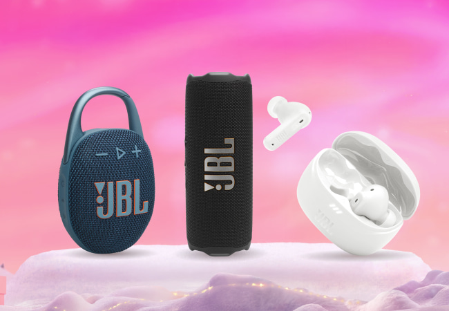 Three JBL audio products (a blue Clip speaker, a black Flip speaker, and white wireless earbuds with their open charging case) displayed on snowy ground against a pink background.