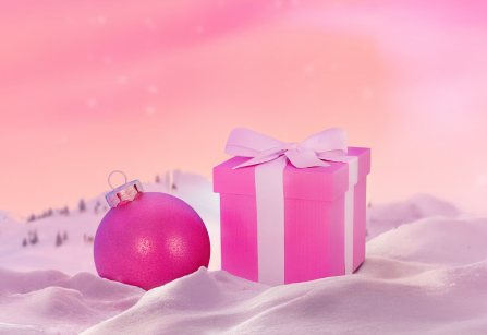 Pink gift box with a white ribbon and a pink Christmas ornament in the snow.