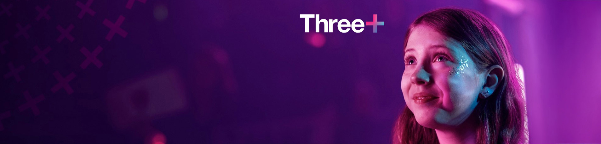 A girl with glitter on her face, possibly at a concert, looks up with a smile. The image has a purple and pink color scheme and the "Three+" logo is in the top right corner.