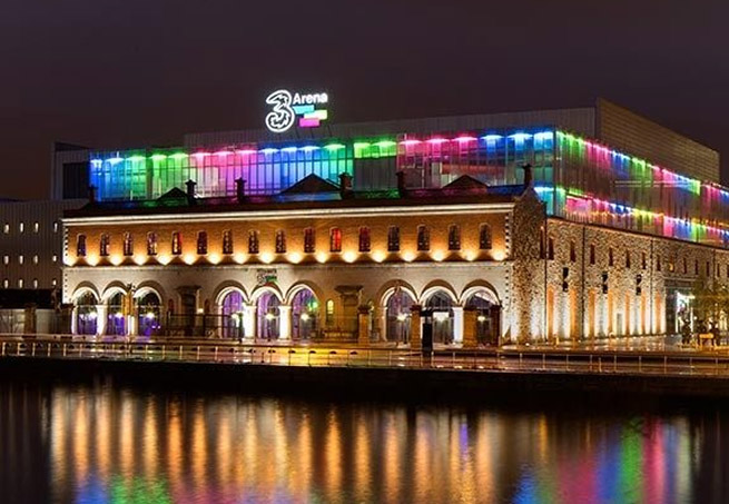 The 3Arena Dublin lit up with colourful lights reflected in the River Liffey at night