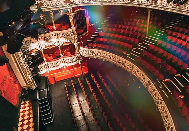 Aerial view of an ornate theatre interior with red seating and decorative gold balconies