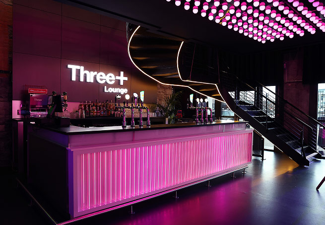 The Three+ Lounge bar lit up in pink and purple neon lighting