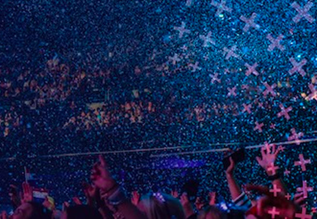 Crowd celebrating at a live event as blue confetti fills the arena.