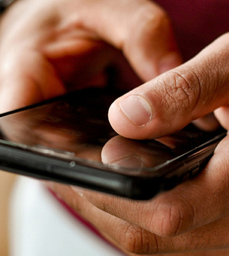Close-up of hands typing on a smartphone.