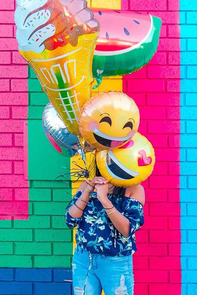 A woman holding a selection of colourful balloons.