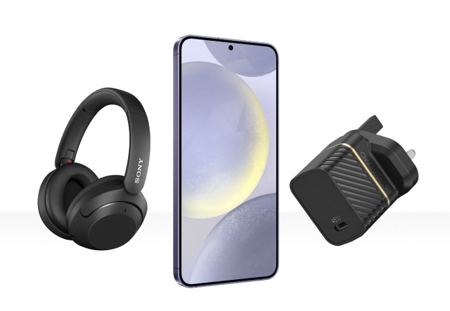 Black Sony headphones, a smartphone, and a wall charger displayed on white background.
