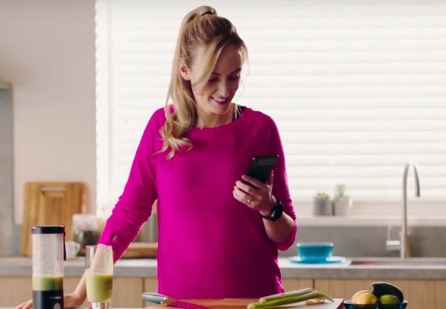 A woman using her phone in the kitchen.