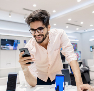 A man viewing a phone inside a Three store. A man viewing a phone inside a Three store.